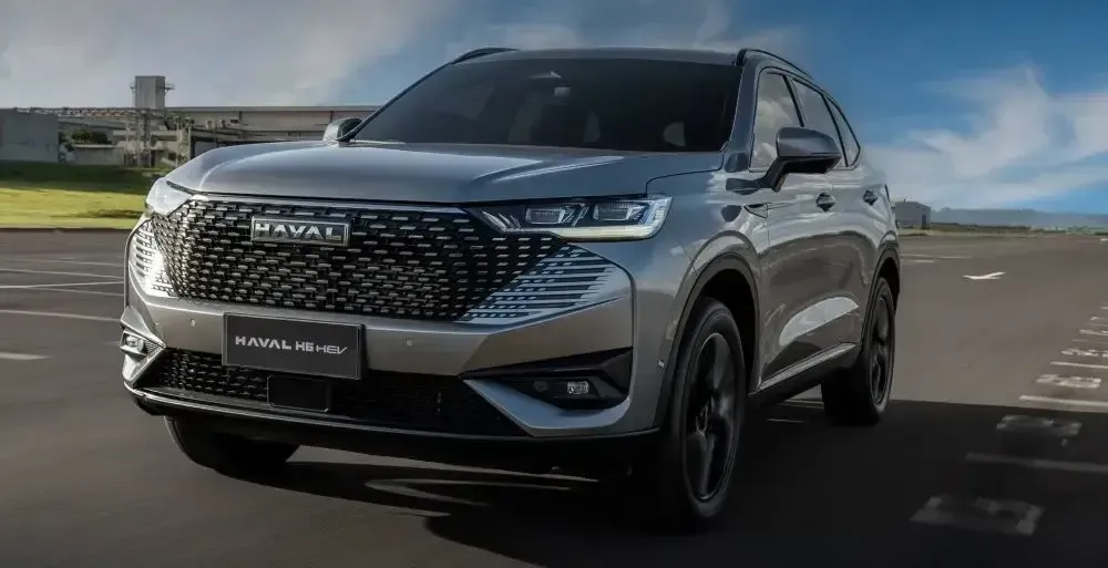 Un SUV plateado circulando por una carretera bajo un cielo despejado.