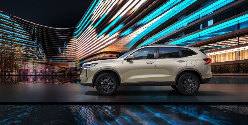 Un SUV beige circulando por un túnel urbano iluminado con luces de neón por la noche.