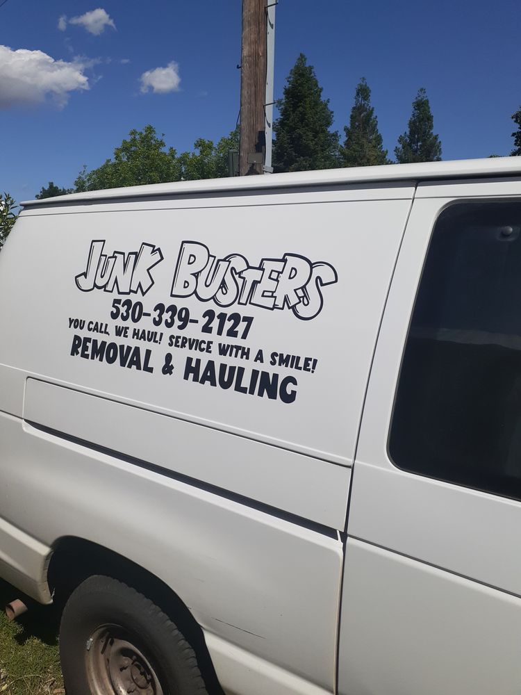 White Junk Busters hauling van with logo, phone number, and service text on the side.
