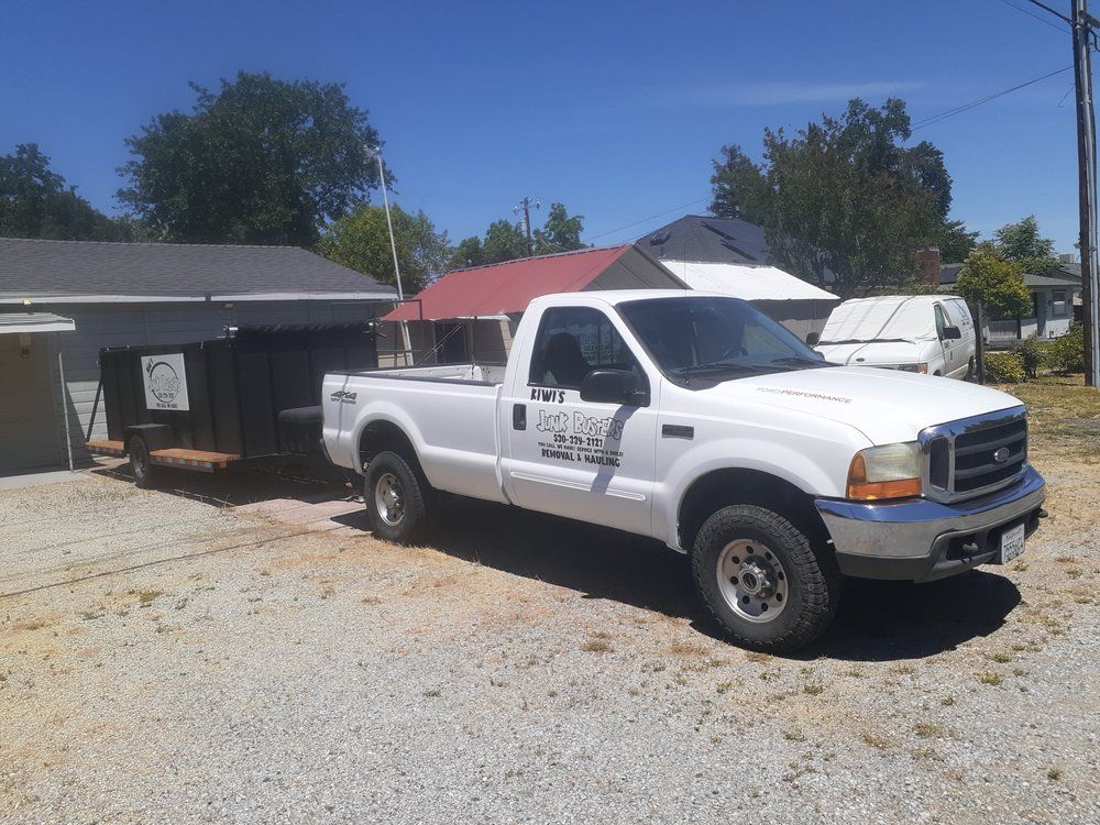 White pickup truck parked in a gravel driveway beside a house and carport on a sunny day