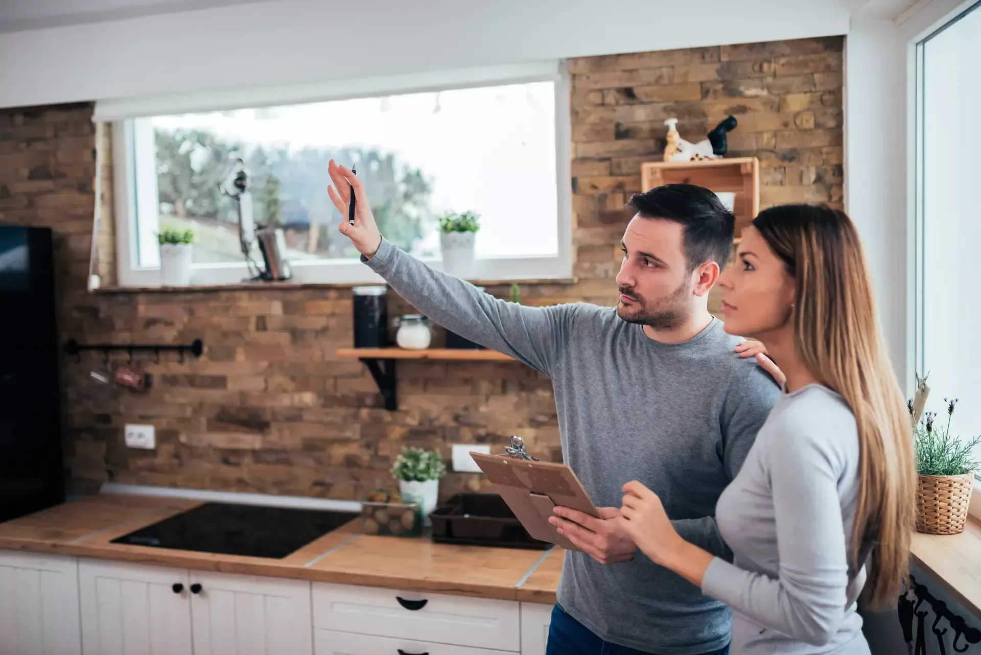 A man and a woman are looking at a tablet in a kitchen.