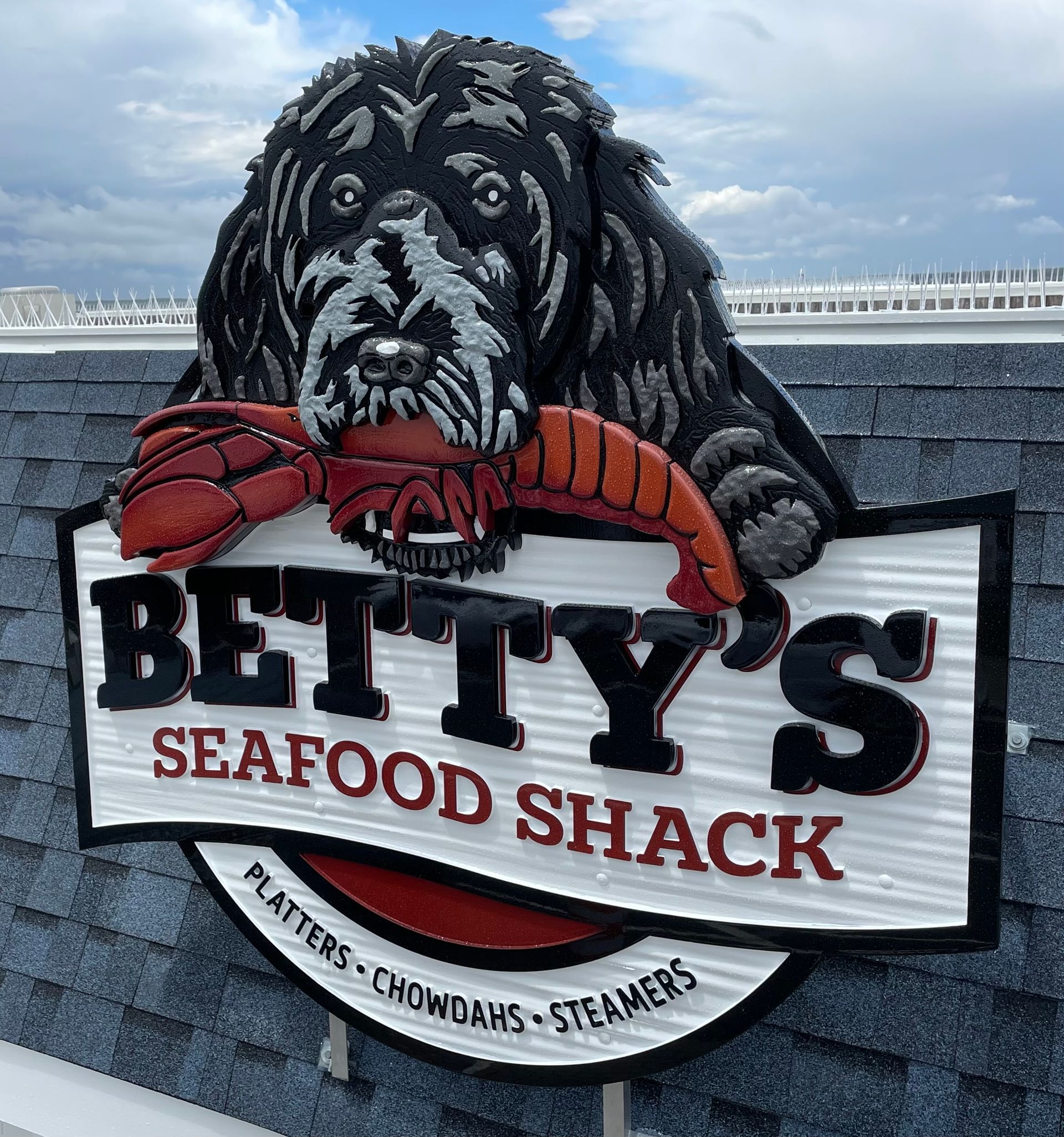 Sign for Betty's Seafood Shack: a black dog holding a red lobster, with text 