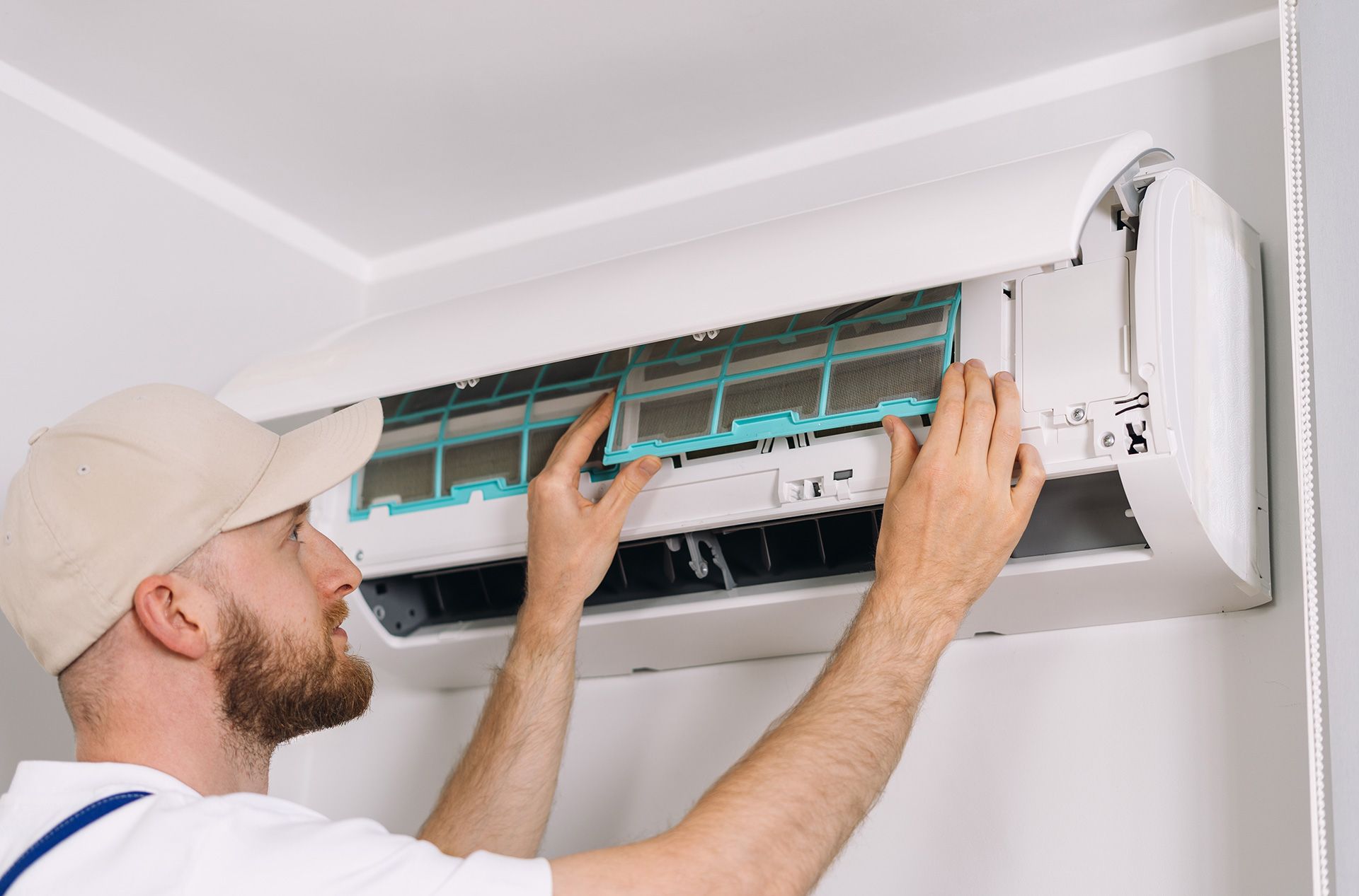 Technician cleaning an indoor wall-mounted air conditioner filter with the cover open