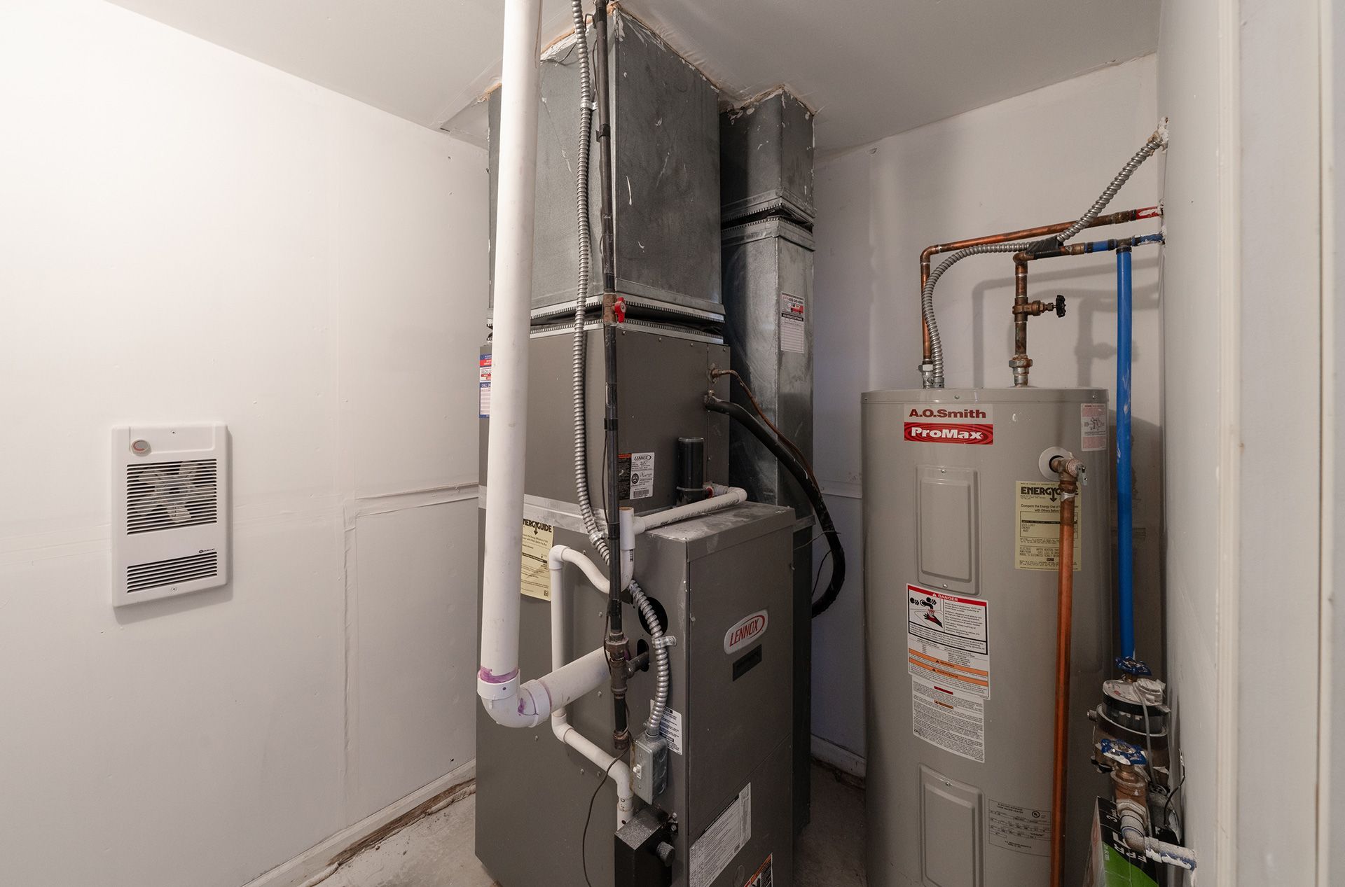 Utility room with HVAC and water heater units, exposed pipes, and ductwork.