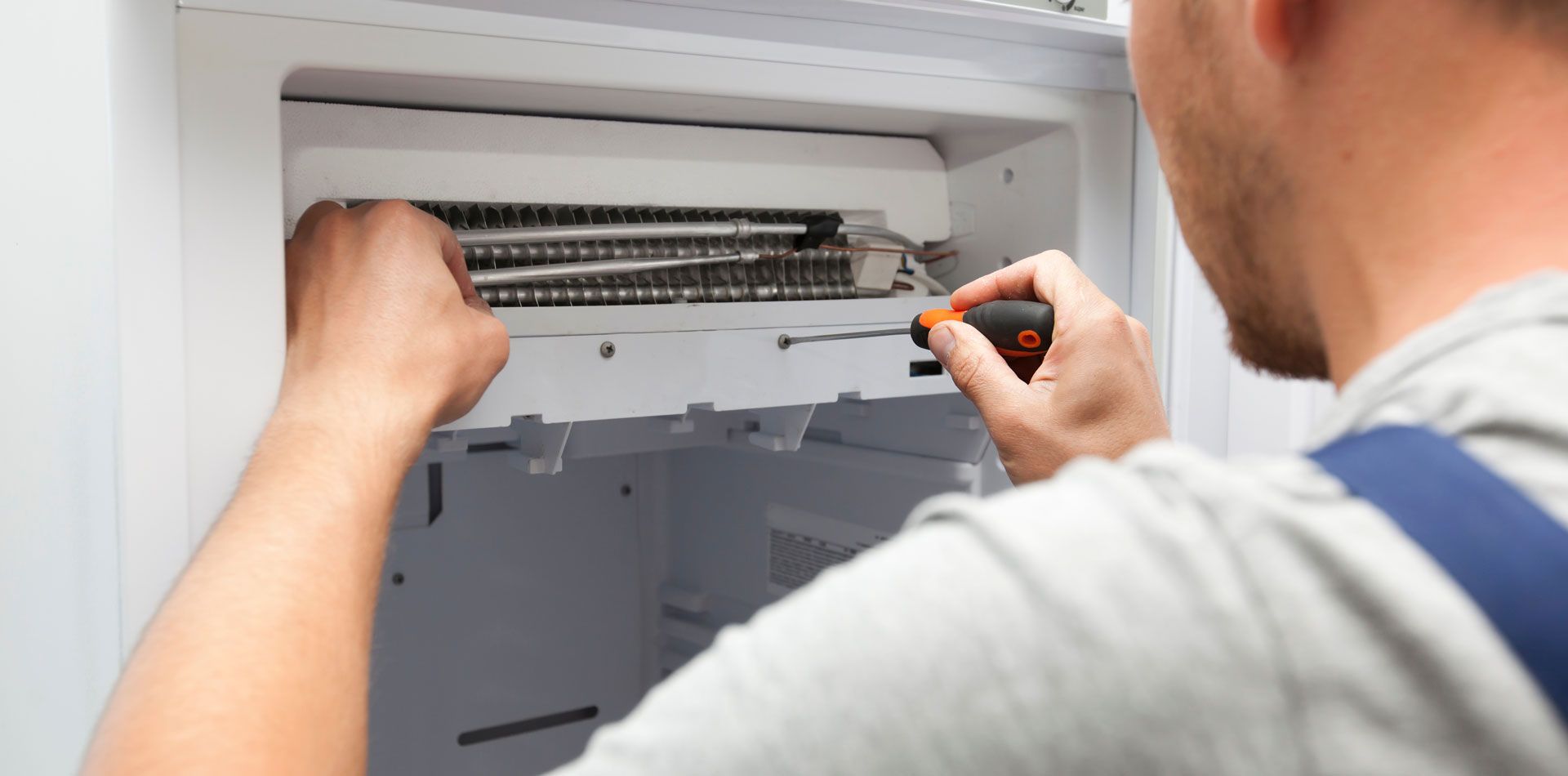 Technician uses a screwdriver to repair an indoor air conditioner unit.