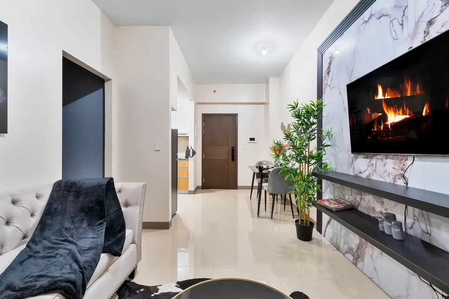 A living room with a fireplace and a flat screen tv.  The Den at Bayshore Luxe by Prime, Manila