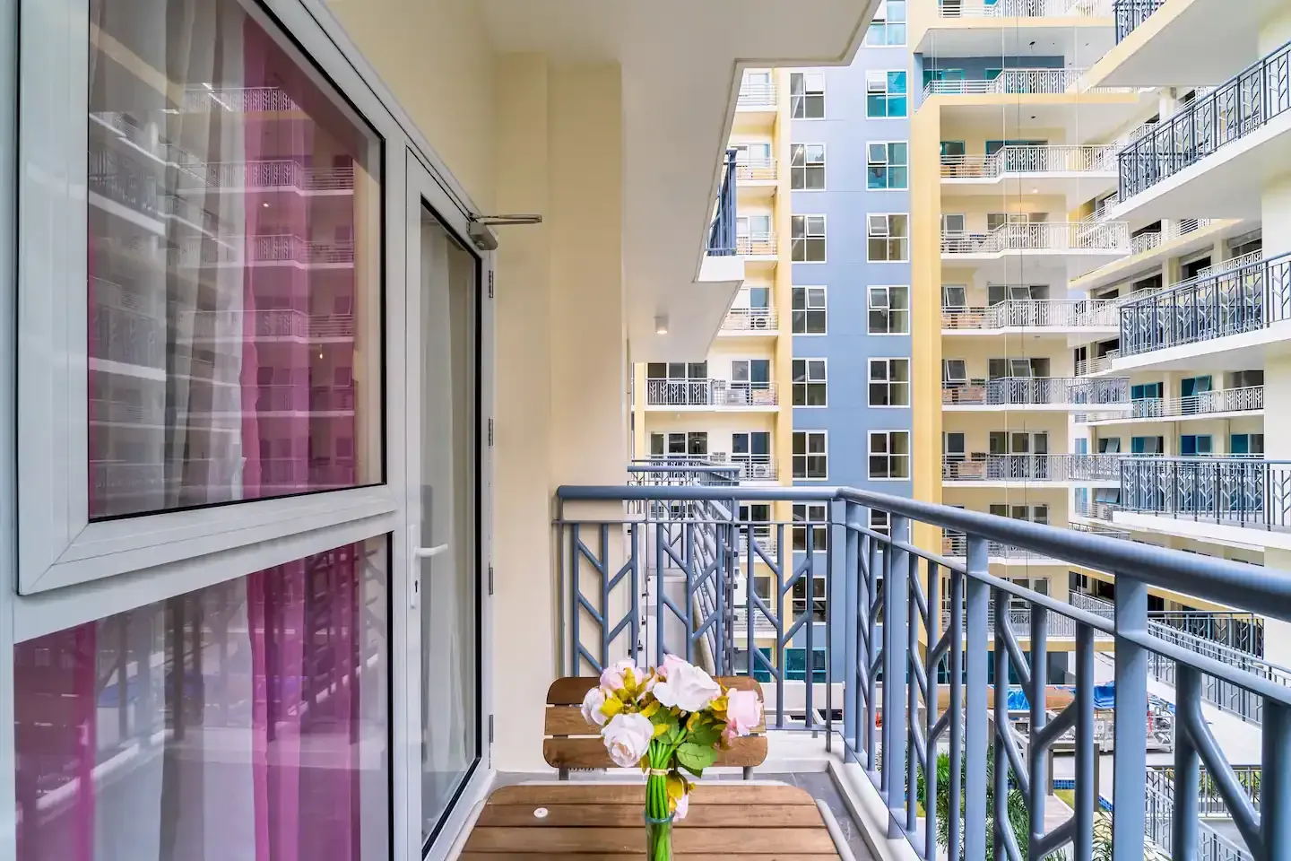 A balcony with a table and chairs and a vase of flowers.  Taylor Swift themed suite at Bayshore Luxe by Prime, Manila