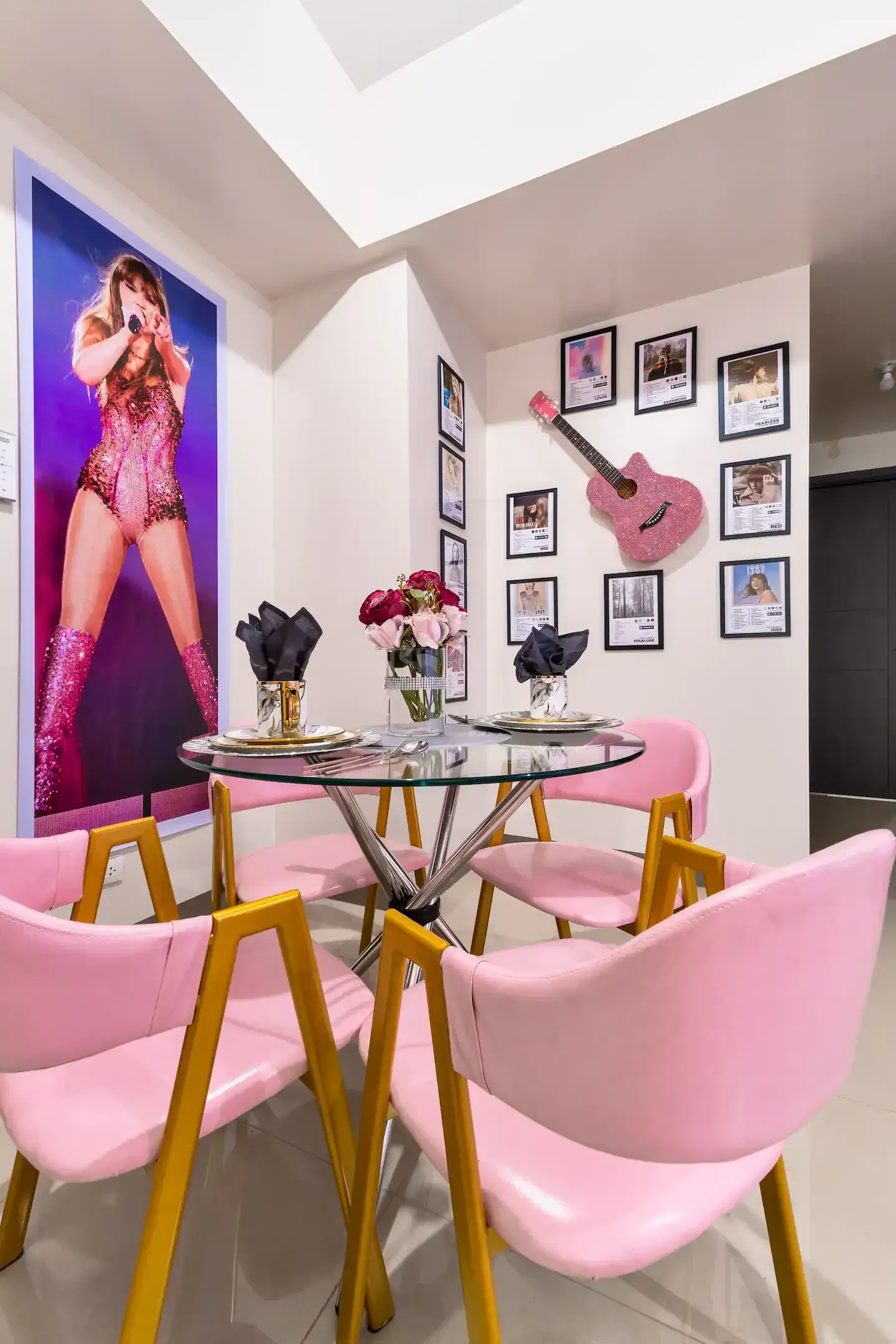 A dining room with pink chairs, and a pink guitar and poster of Taylor Swift on the wall at Bayshore Luxe by Prime, Manila
