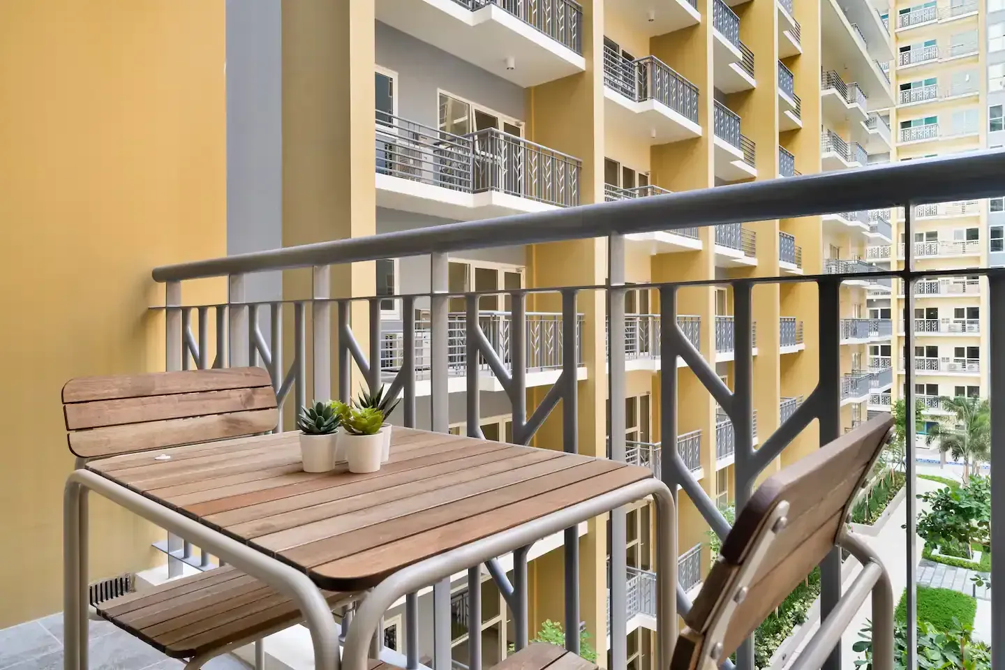 A balcony with a table and chairs in front of a building.  The Den at Bayshore Luxe by Prime, Manila