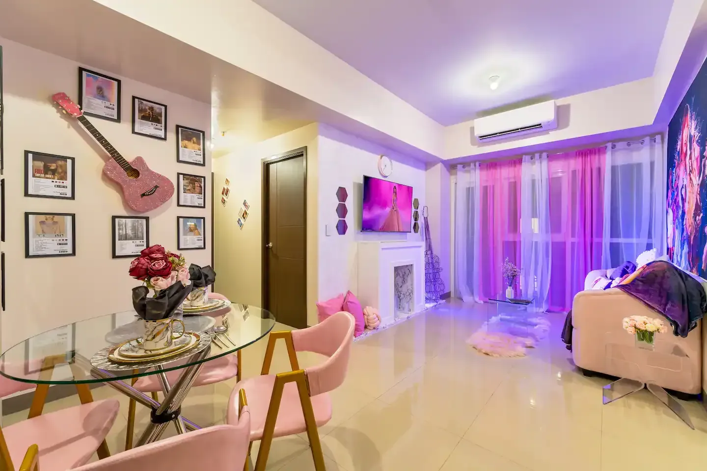 A Taylor Swift themed living room with table, pink chairs and sofa and a guitar on the wall at Bayshore Luxe by Prime, Manila