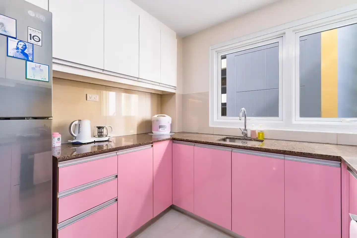 A kitchen with pink cabinets and a stainless steel refrigerator at Bayshore Luxe by Prime, Manila