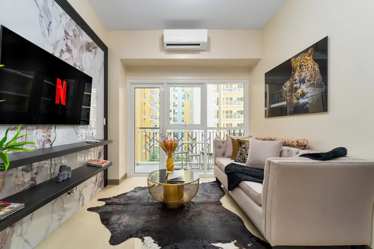 A living room with a couch and a flat screen tv on the wall.   The Den at Bayshore Luxe by Prime, Manila