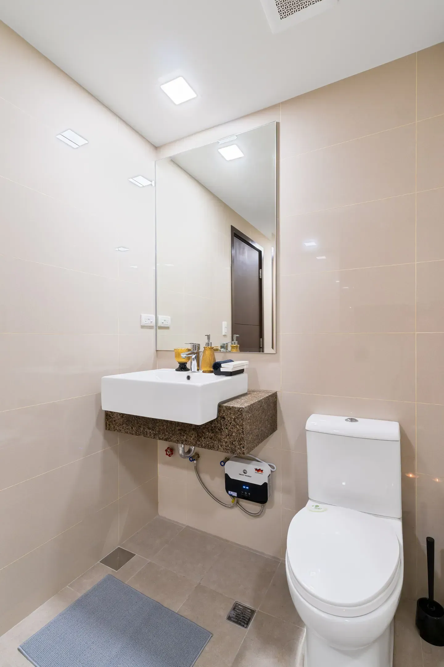 A bathroom with a toilet , sink and mirror.   The Den at Bayshore Luxe by Prime, Manila