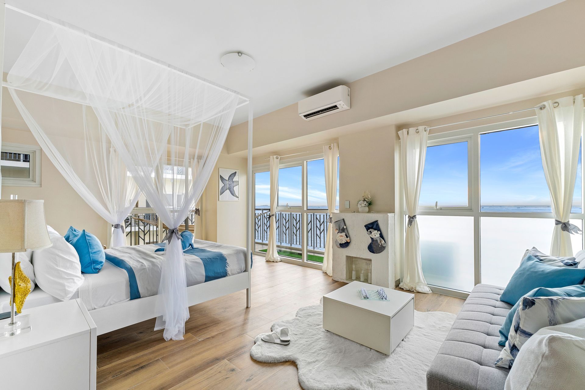 Bedroom with four poster bed, with white and blue linens, balcony door and faux fireplace