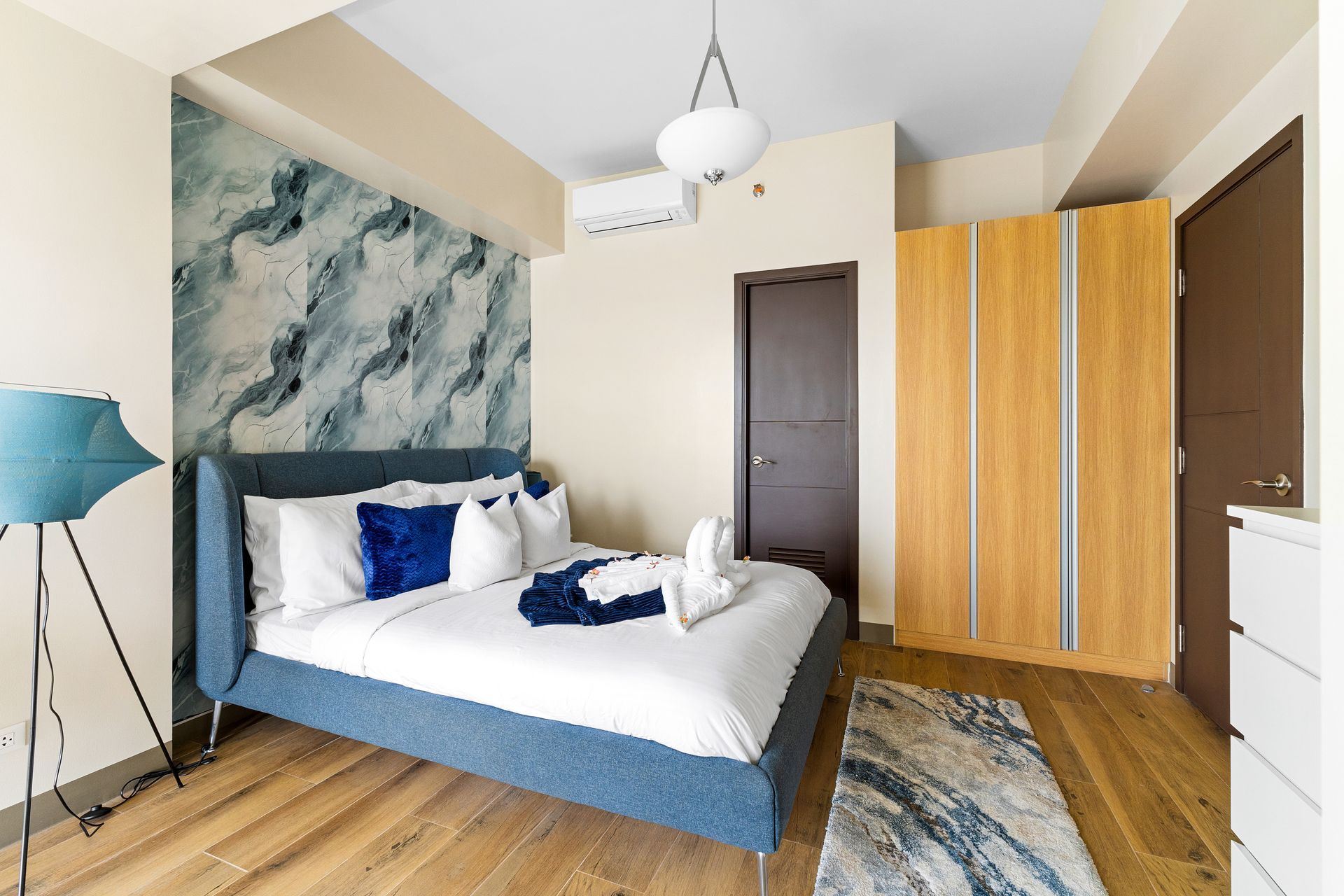 Bedroom decorated in blues and white linens with a triple wardrobe and white chest of drawers