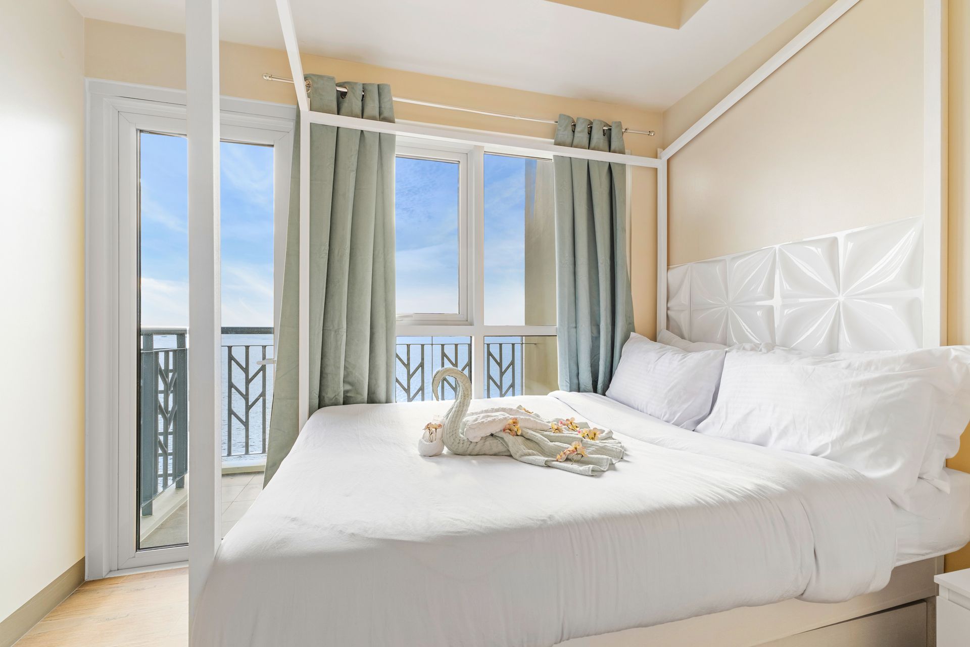 Bedroom with four poster bed, with white linens, balcony door and ocean views
