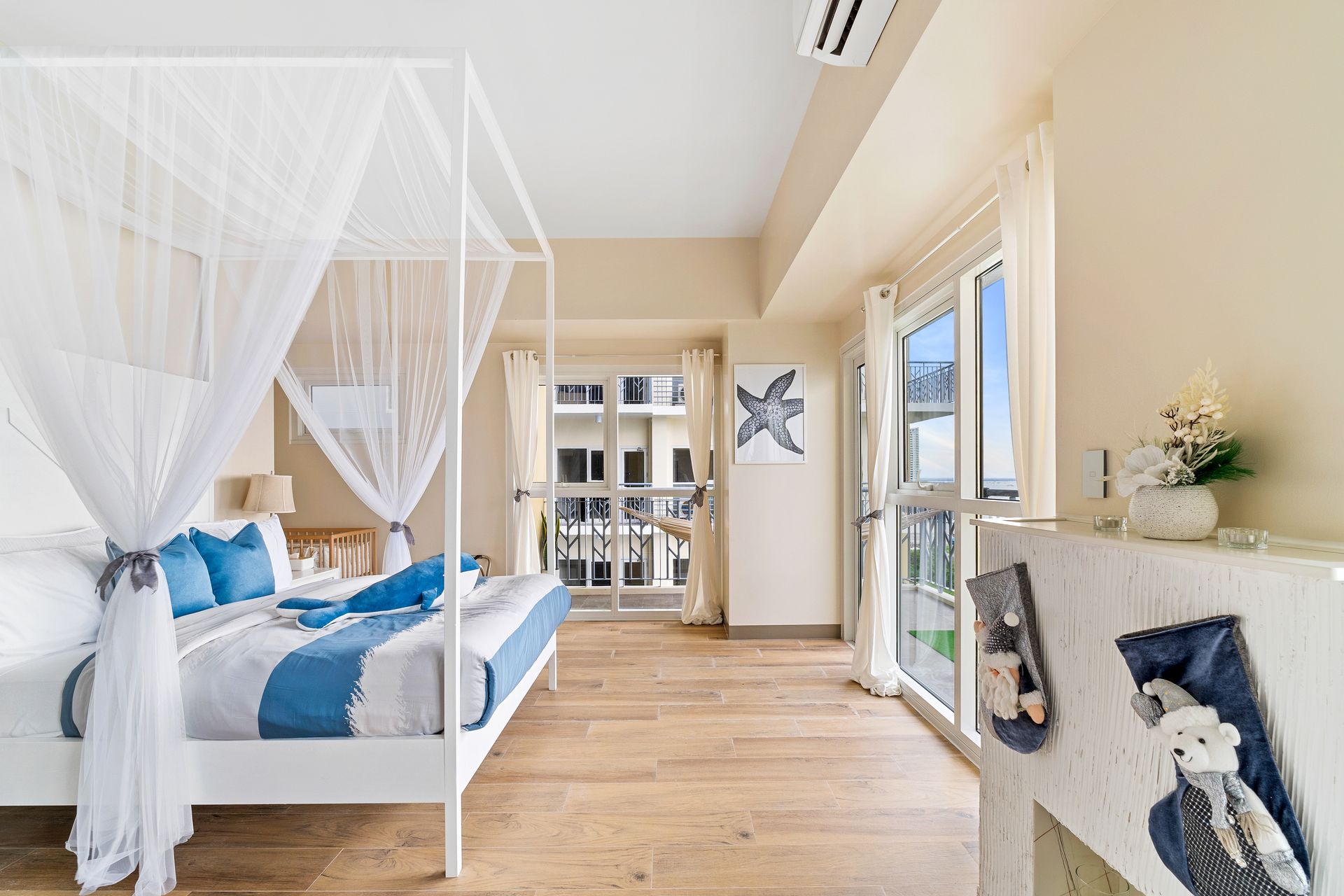 Bedroom with four poster bed, with white and blue linens, balcony door and faux fireplace