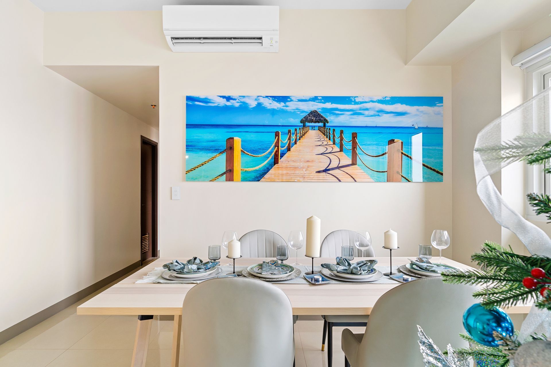 Long white dining table, with gray faux leather chairs, a photo of a tropical dock on the wall behind