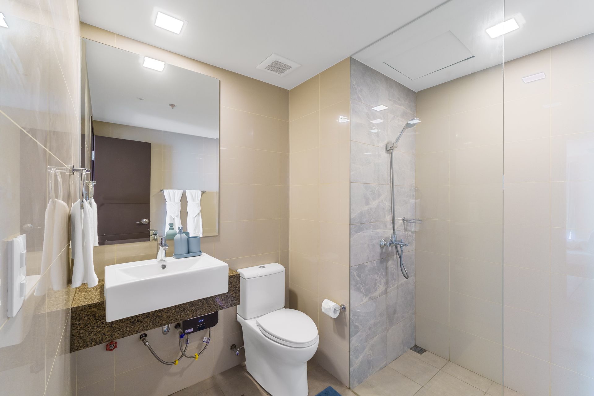 Modern white bathroom with sink, tall mirror, toilet and marble effect shower