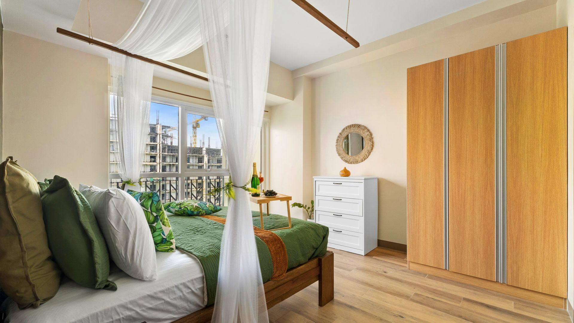 Bed with net curtain surround, green bedding and a wooden closest and white chest of drawers