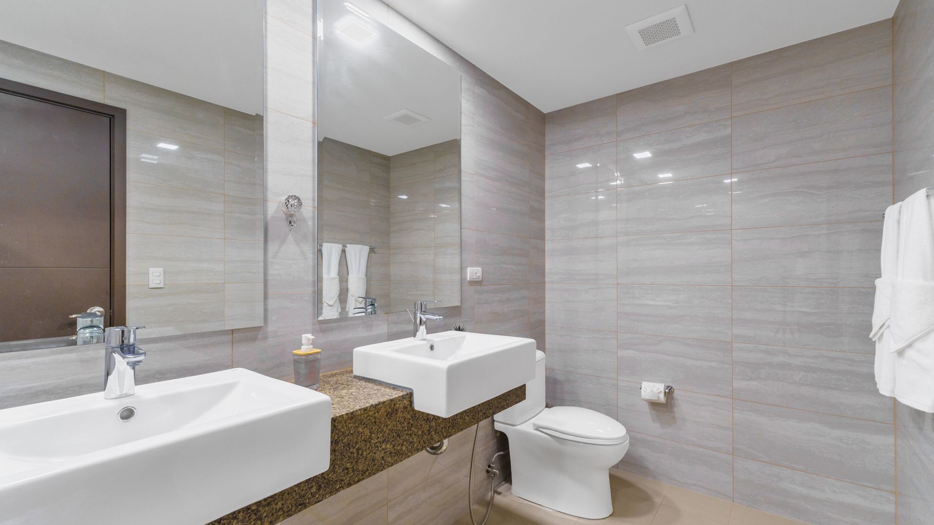 Double bathroom sink counter top with mirrors and a toilet to the side