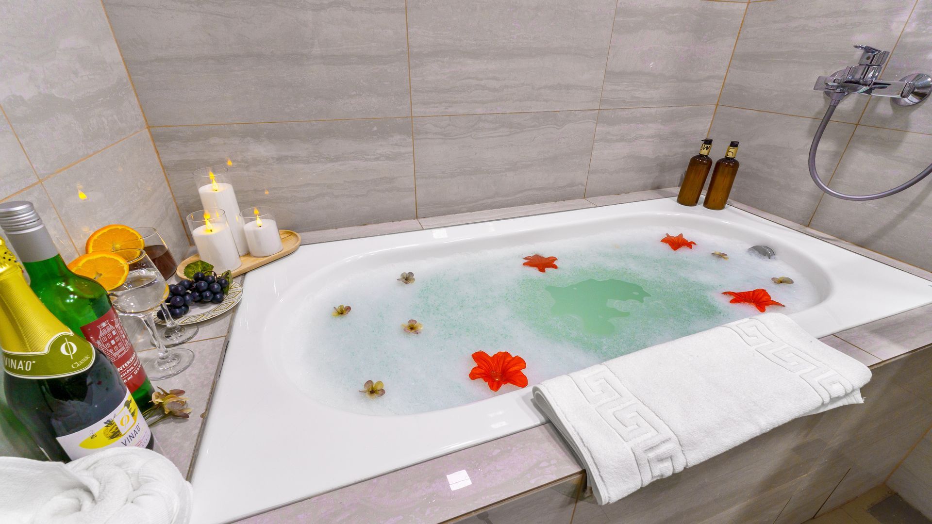Bathtub with water and flowers in it, candles around the edge