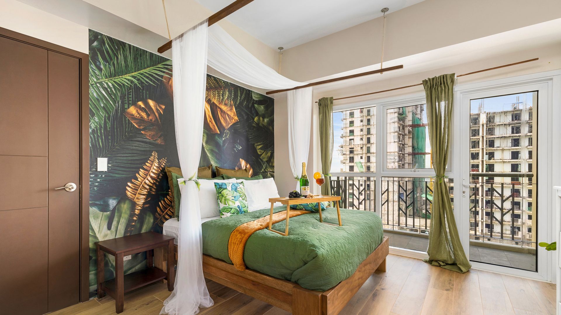 Bed with white curtain surround and green bedding, Tropical feature wall behind