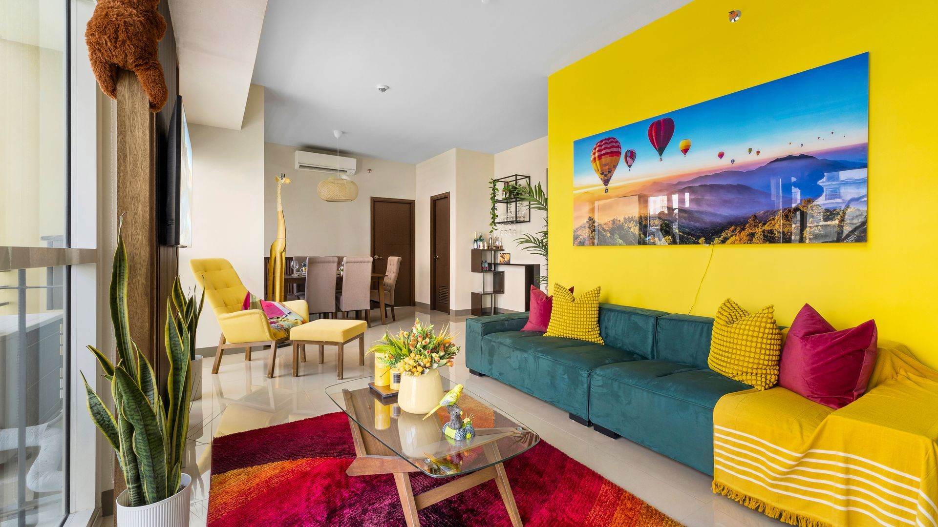 Living room with deep green sofa, yellow armchair, tropical feature wall and TV