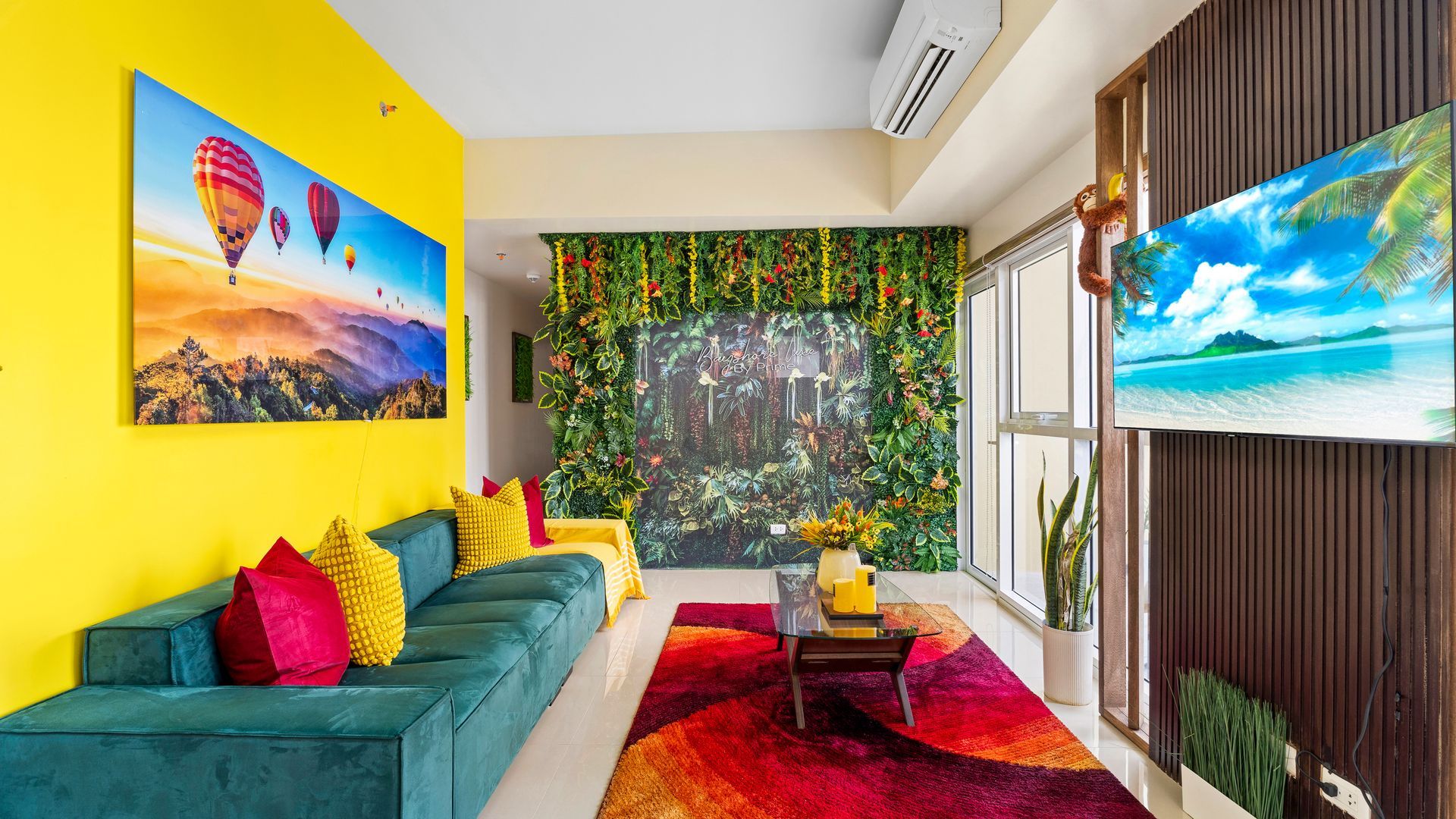 Living room with deep green sofa, yellow armchair, tropical feature wall and TV