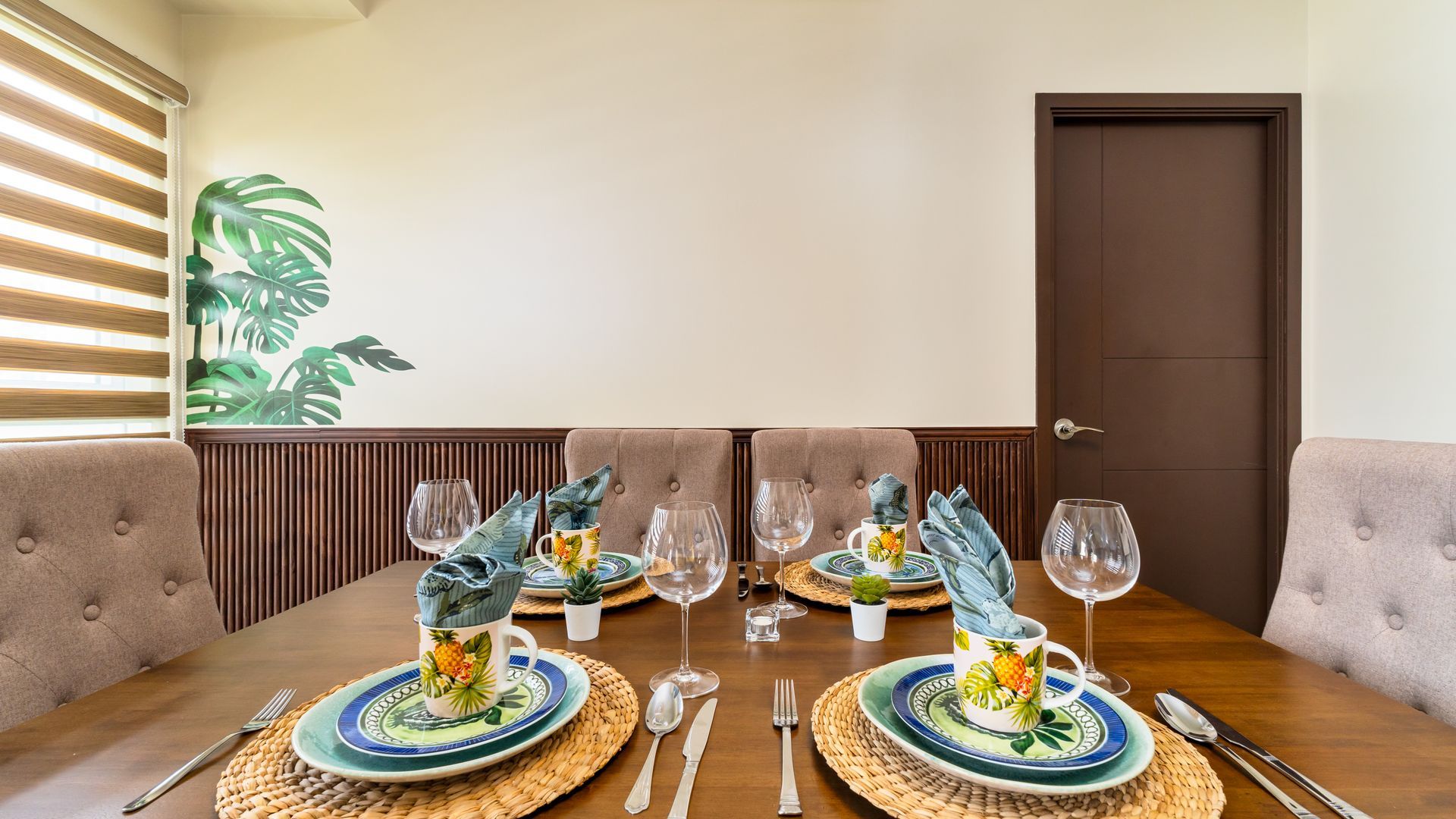 Dining table with faux suede beige chairs and tropical plates  and cups