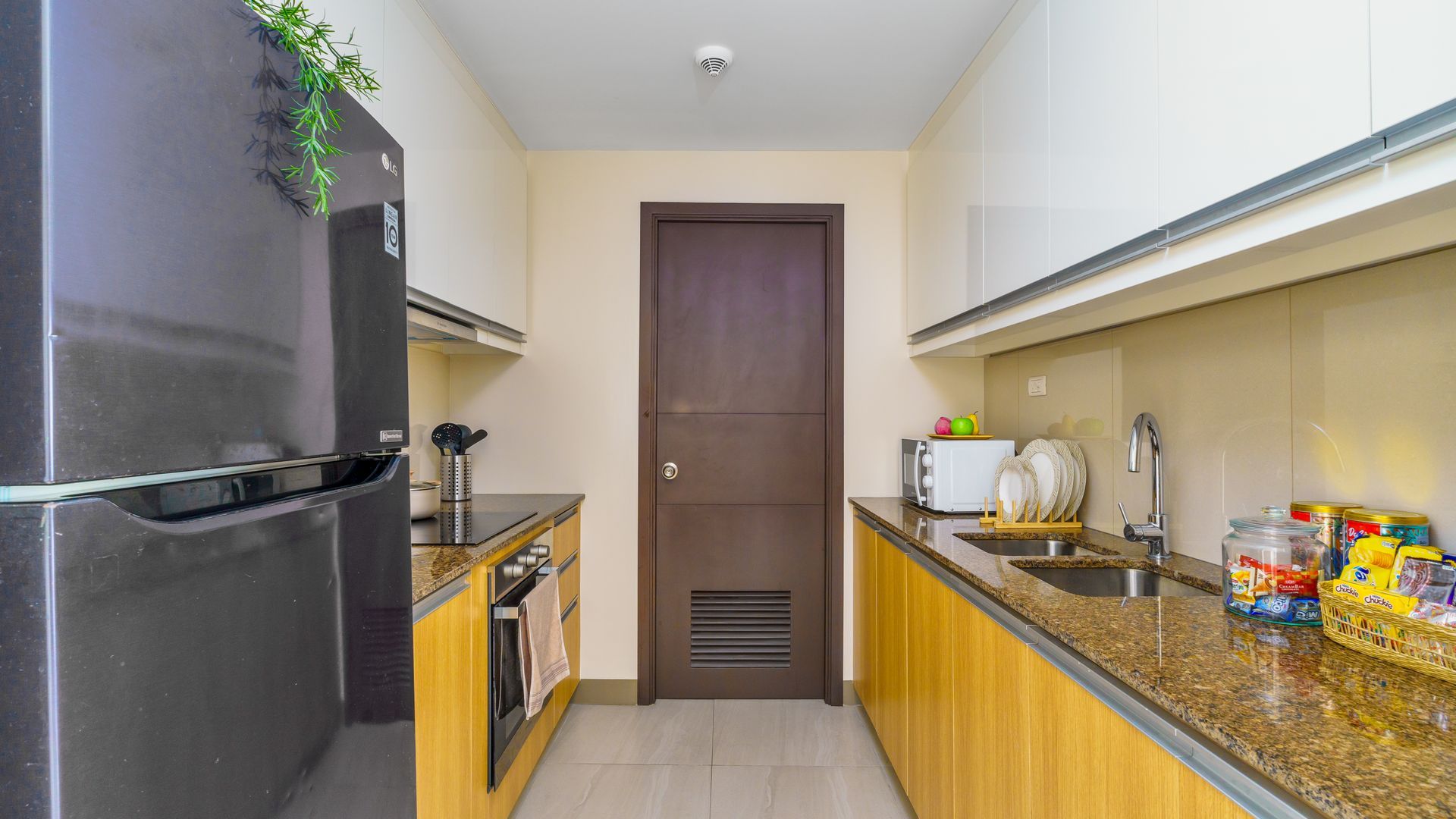 Tall Fridge Freezer next to a kitchen counter with hobs and oven plus sink opposite