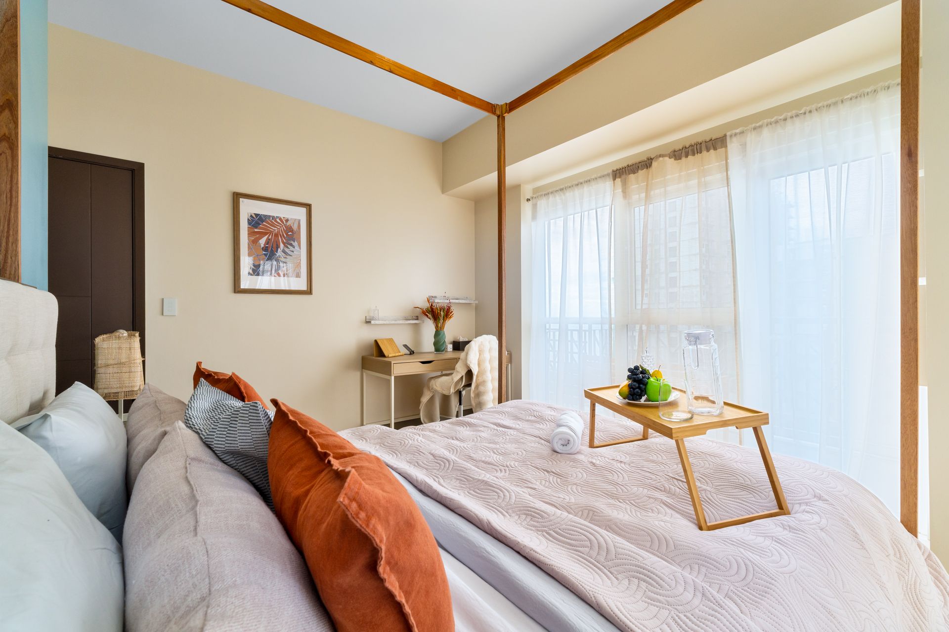 Four poster bed in a bright room with desk, bedside table and curtains