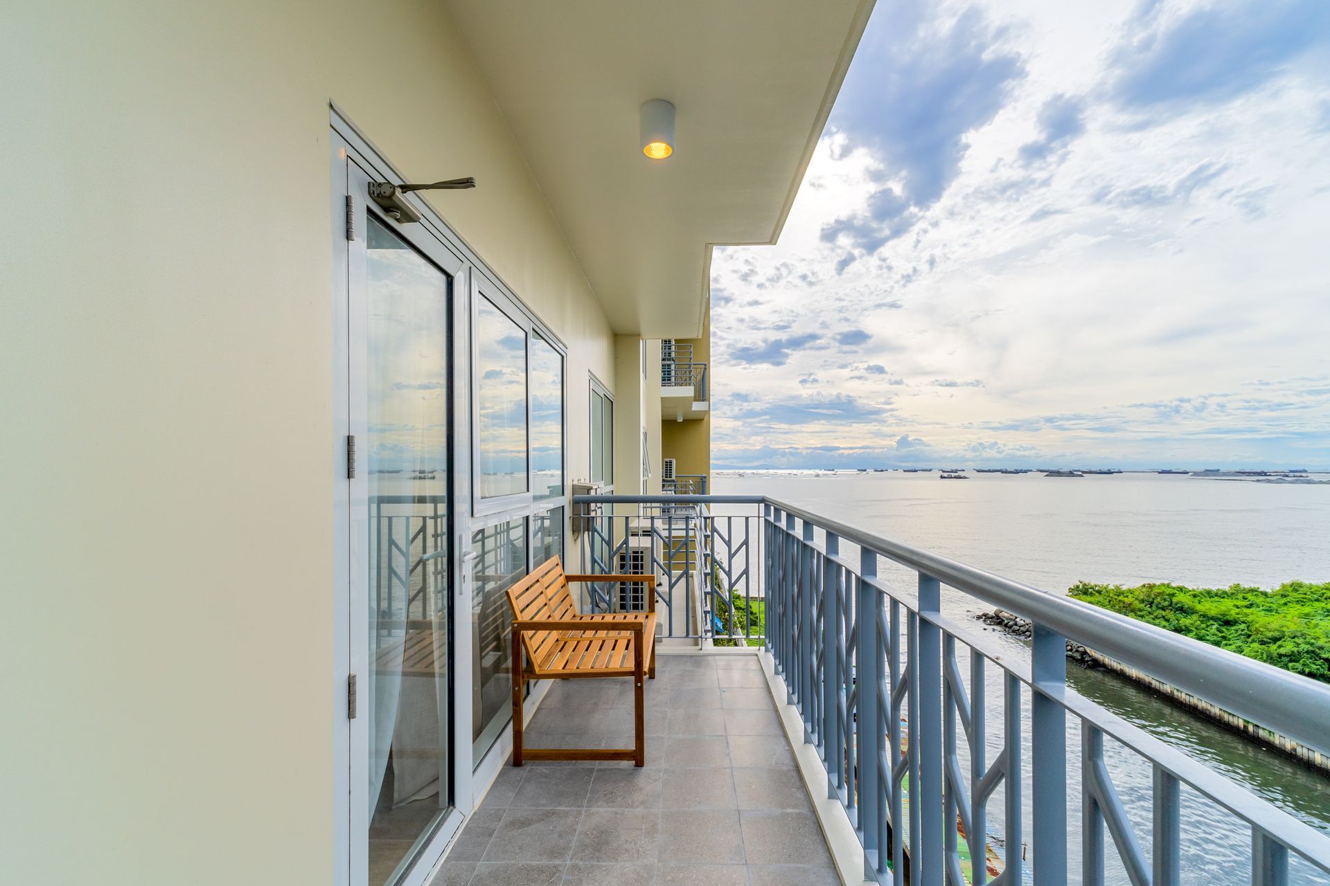 A balcony with a bench and a view of the ocean.