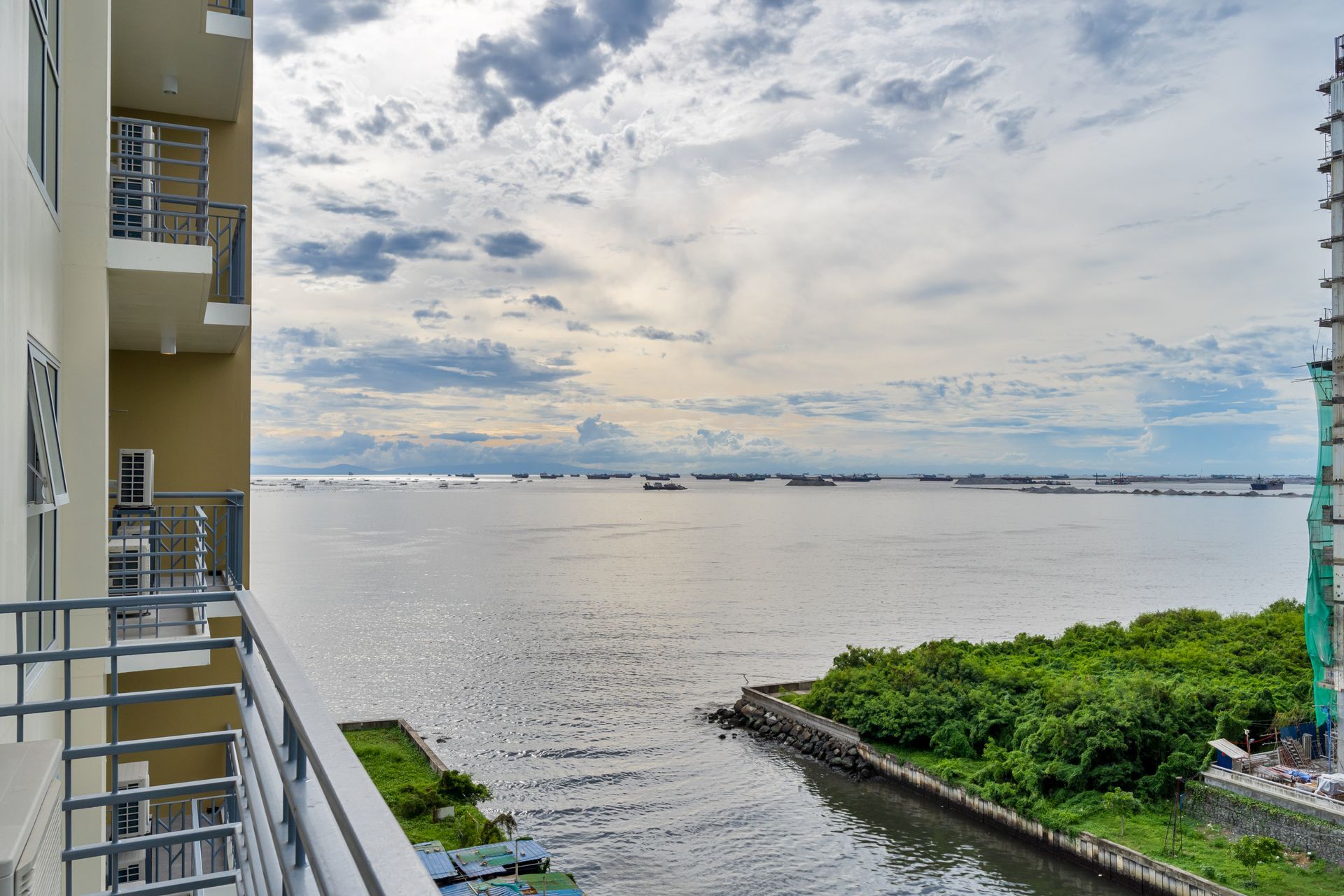 A view of a body of water from a balcony Captains Quarters at Bayshore Luxe by Prime, Manila