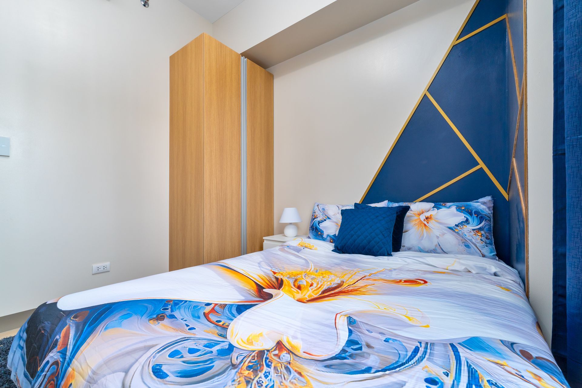 A bed with a blue comforter and pillows in a bedroom.
