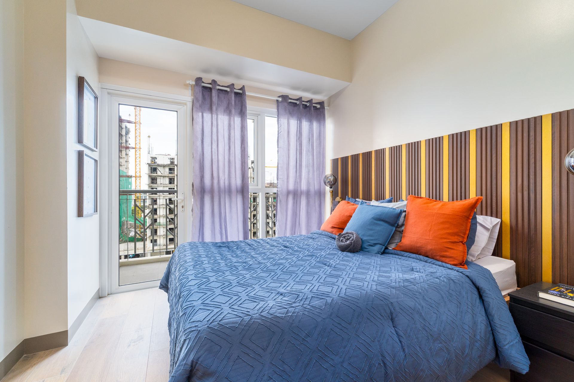 A bedroom with a blue bed and orange pillows.