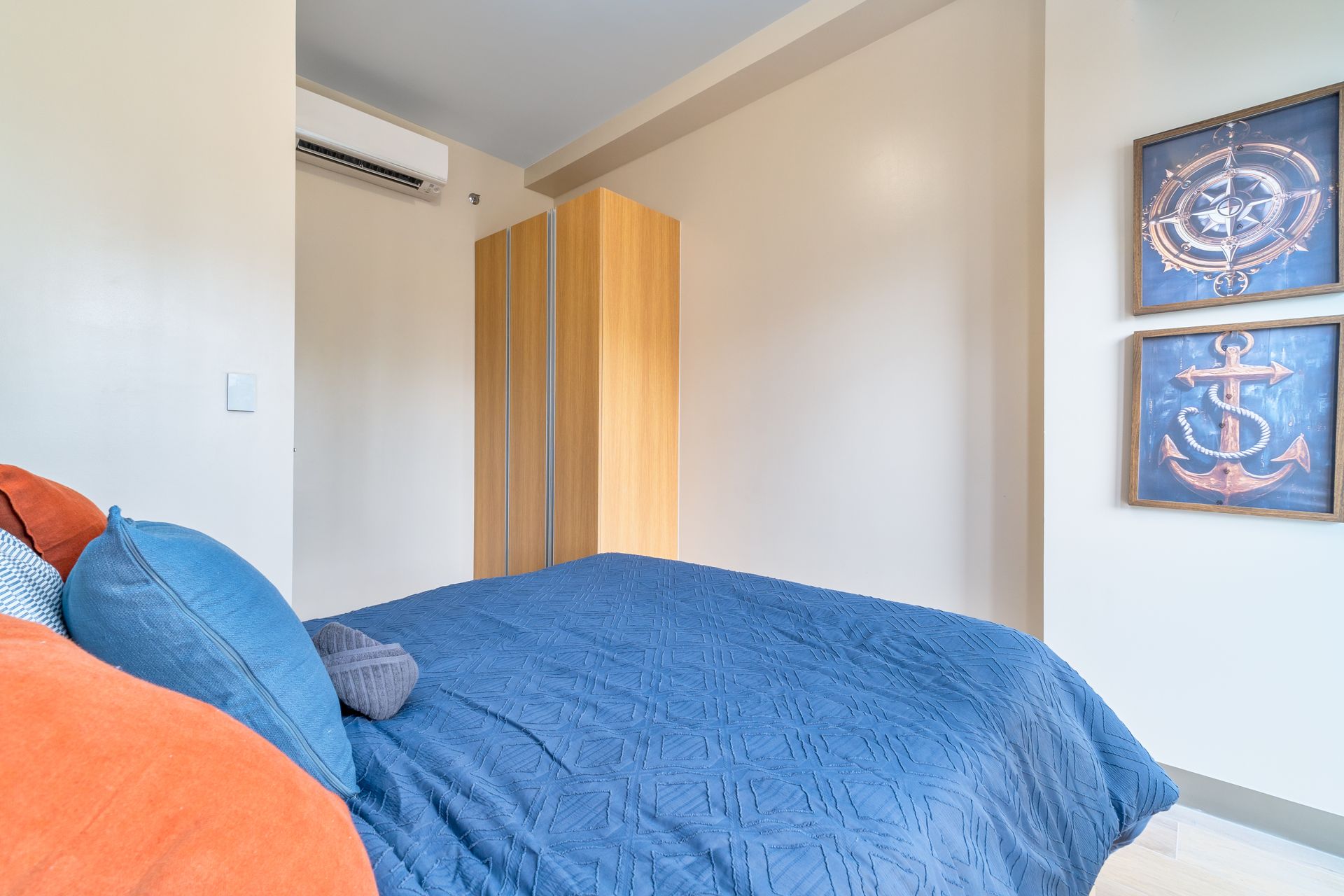A bedroom with a bed and two nautical themed paintings on the wall. Captains Quarters at Bayshore Luxe by Prime, Manila