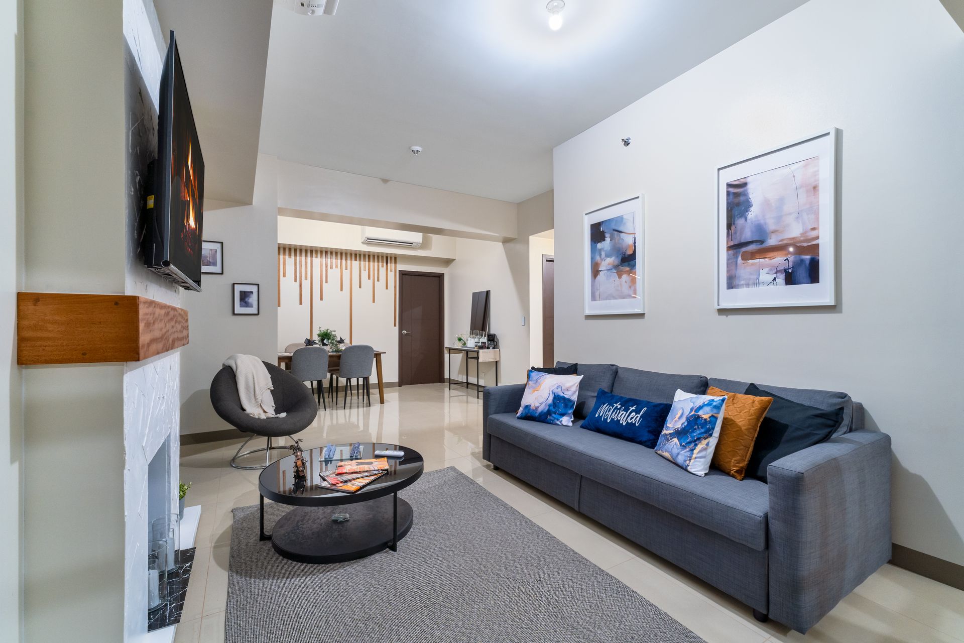A living room with a couch , coffee table , chairs and a fireplace. Captains Quarters at Bayshore Luxe by Prime, Manila
