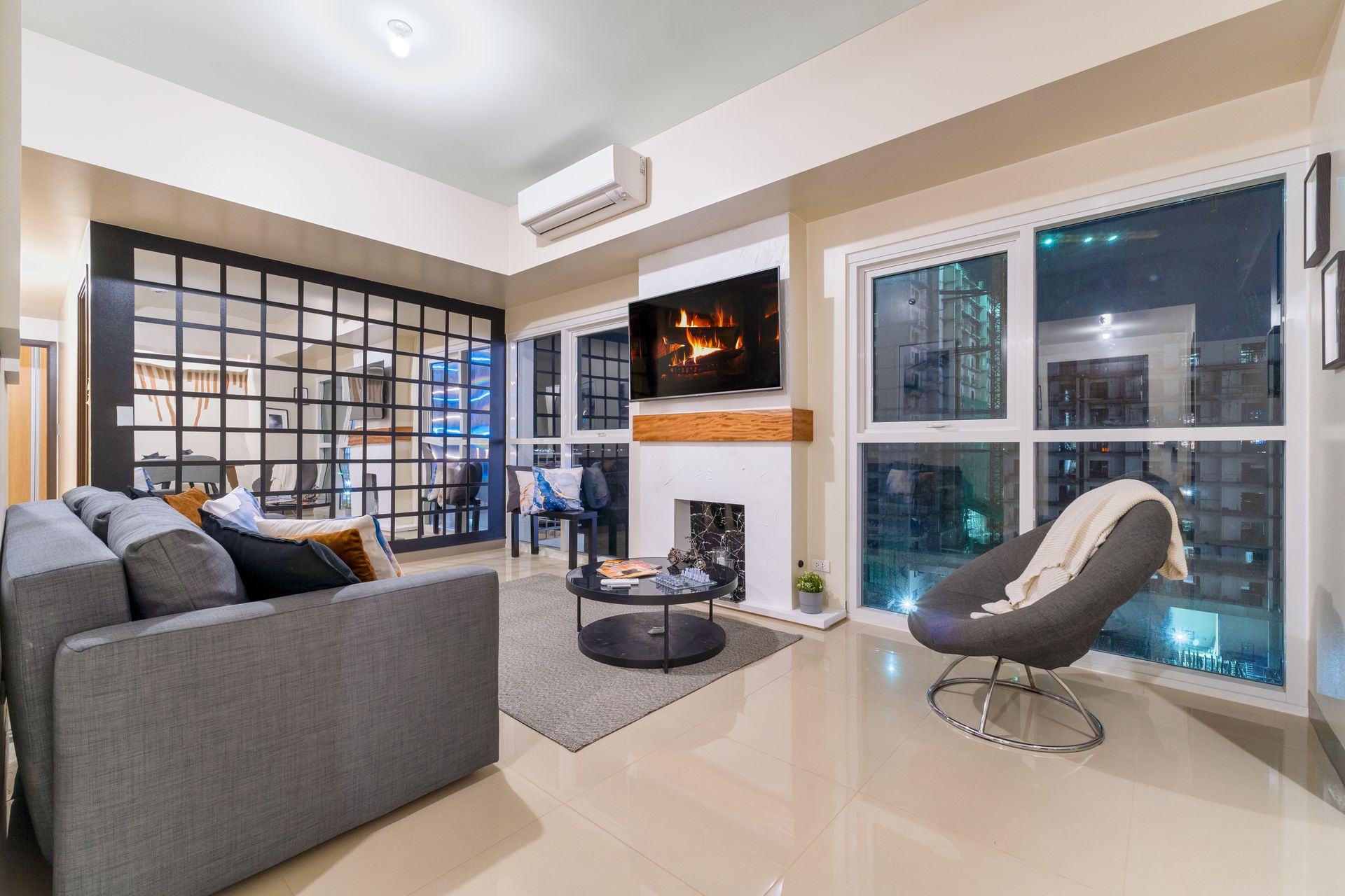 Living room with sofa, chair, coffee table , fireplace & TV.  Captains Quarters 3-bed suite at Bayshore Luxe by Prime, Manila