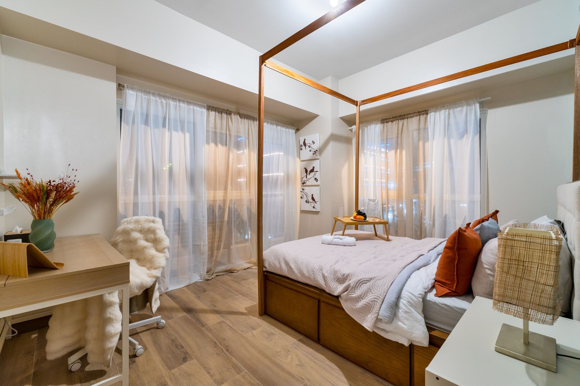 A bedroom with a canopy bed and a desk.  Captains Quarters at Bayshore Luxe by Prime, Manila