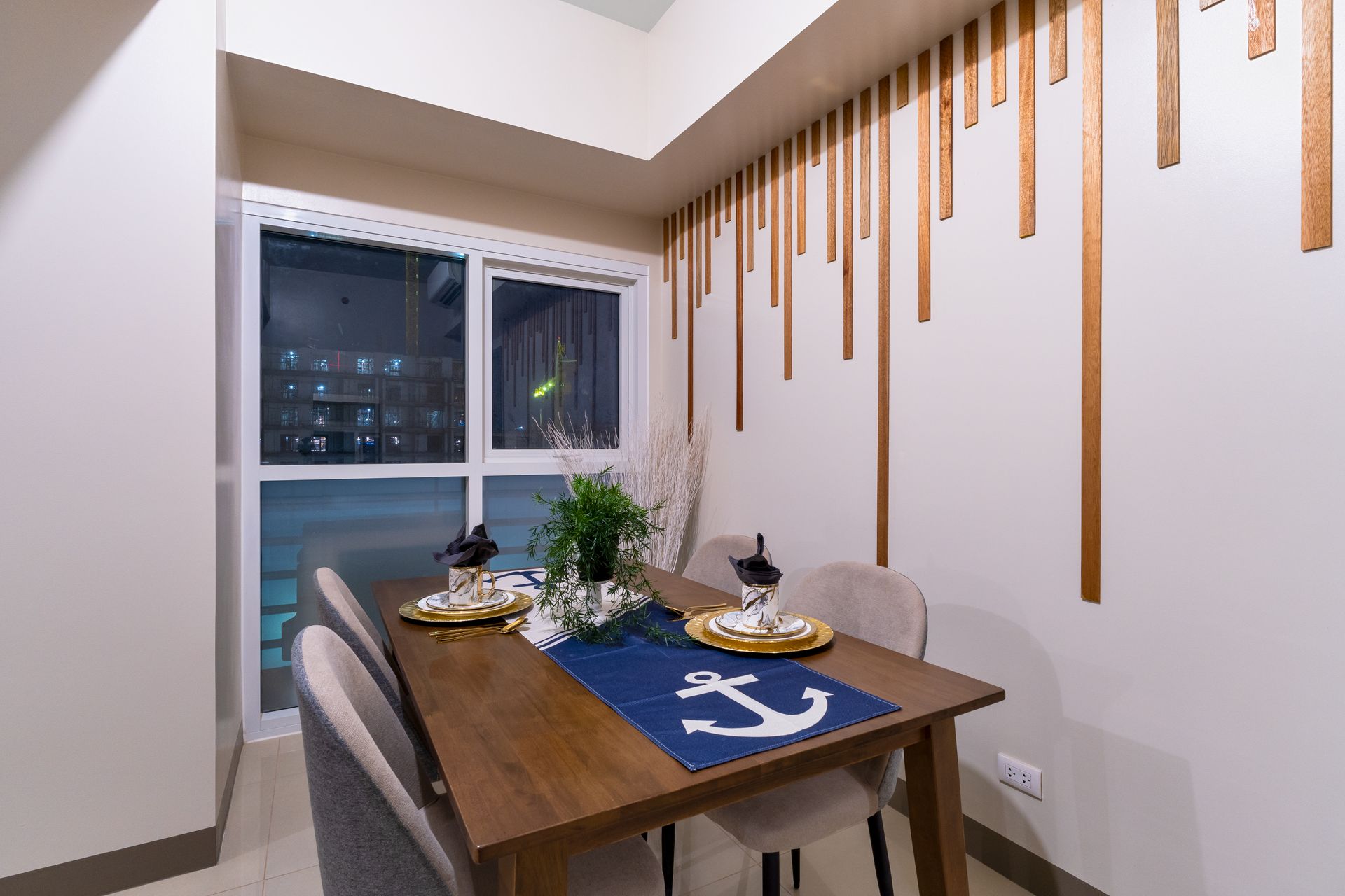 A dining room with a table and chairs and a window. Captains Quarters at Bayshore Luxe by Prime, Manila