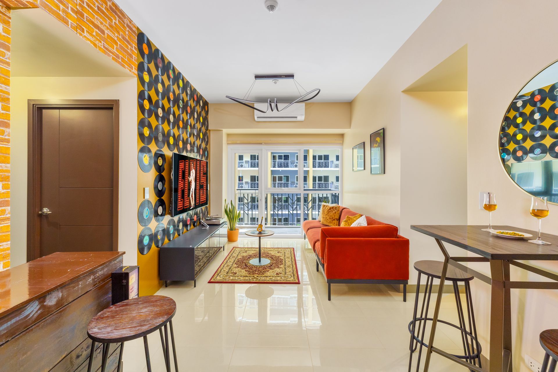 Vibrant living room with orange velvet sofa, Rug and a wall decorated with old vinyl records