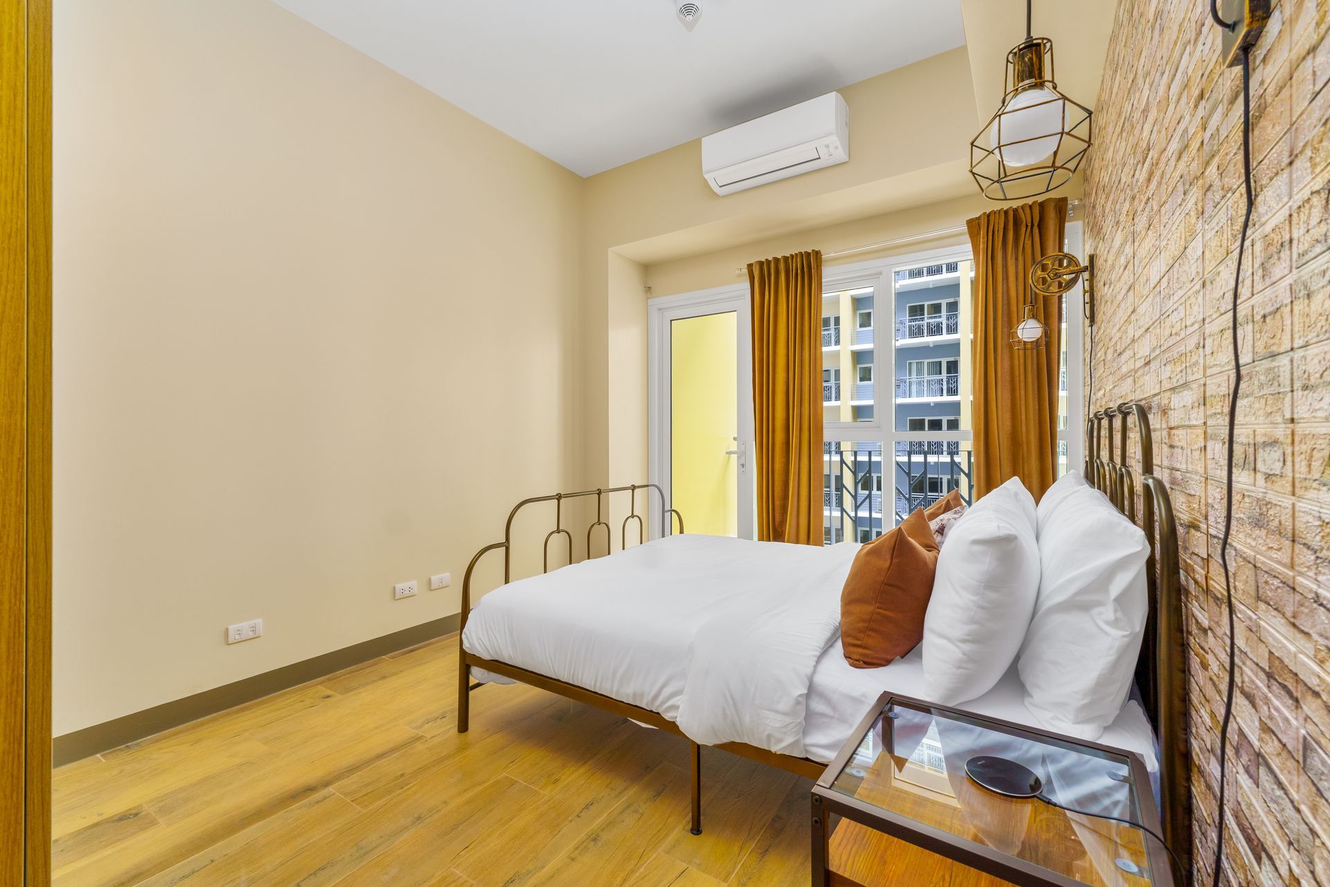 Wrought iron bed with white linens and a brick effect wall feature