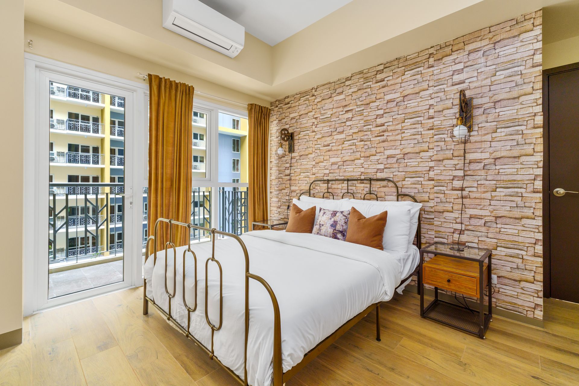 Wrought iron bed with white linens and a brick effect wall feature
