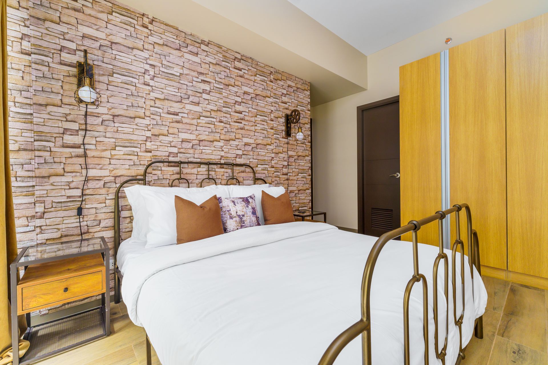 Wrought iron bed with white linens and a brick effect wall feature