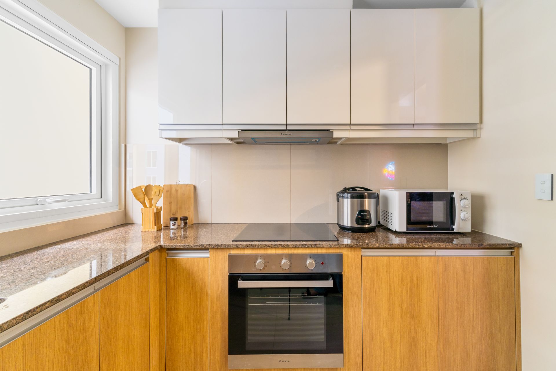 Kitchen counterspace with oven and hobs, cupboard above and a rice cookers and microwave 