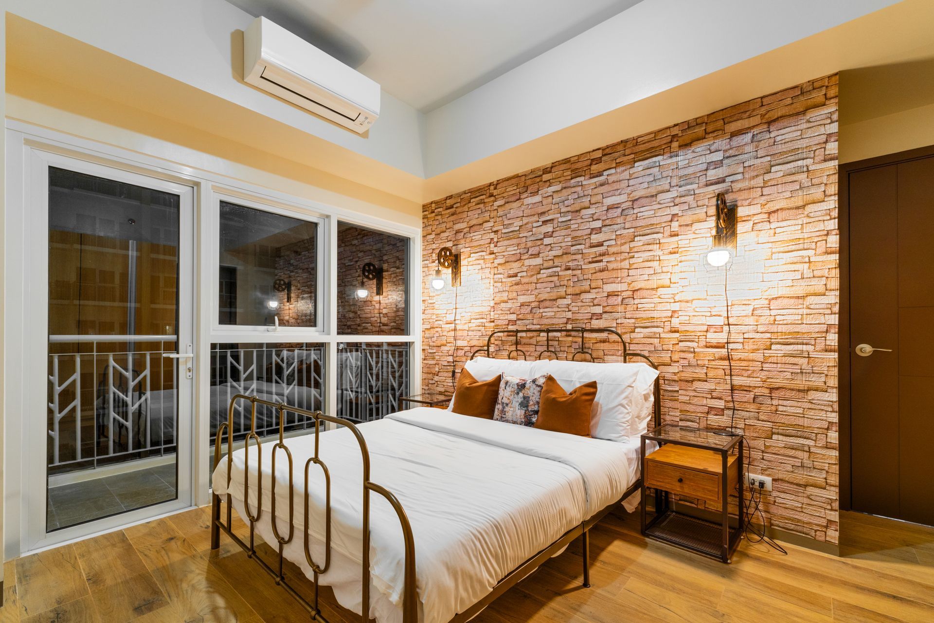 Wrought iron bed with white linens and a brick effect wall feature