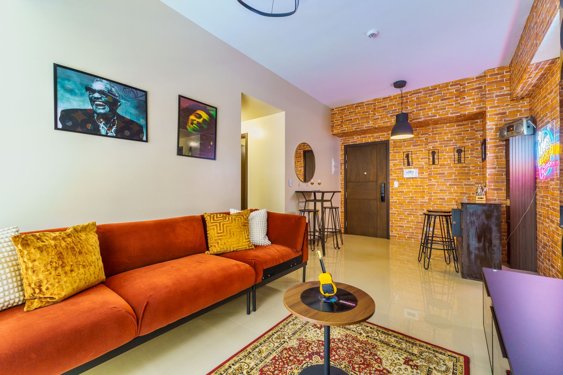 Vibrant living room with orange velvet sofa, Rug and a wall decorated with images of Ray Charles and Bob Marley