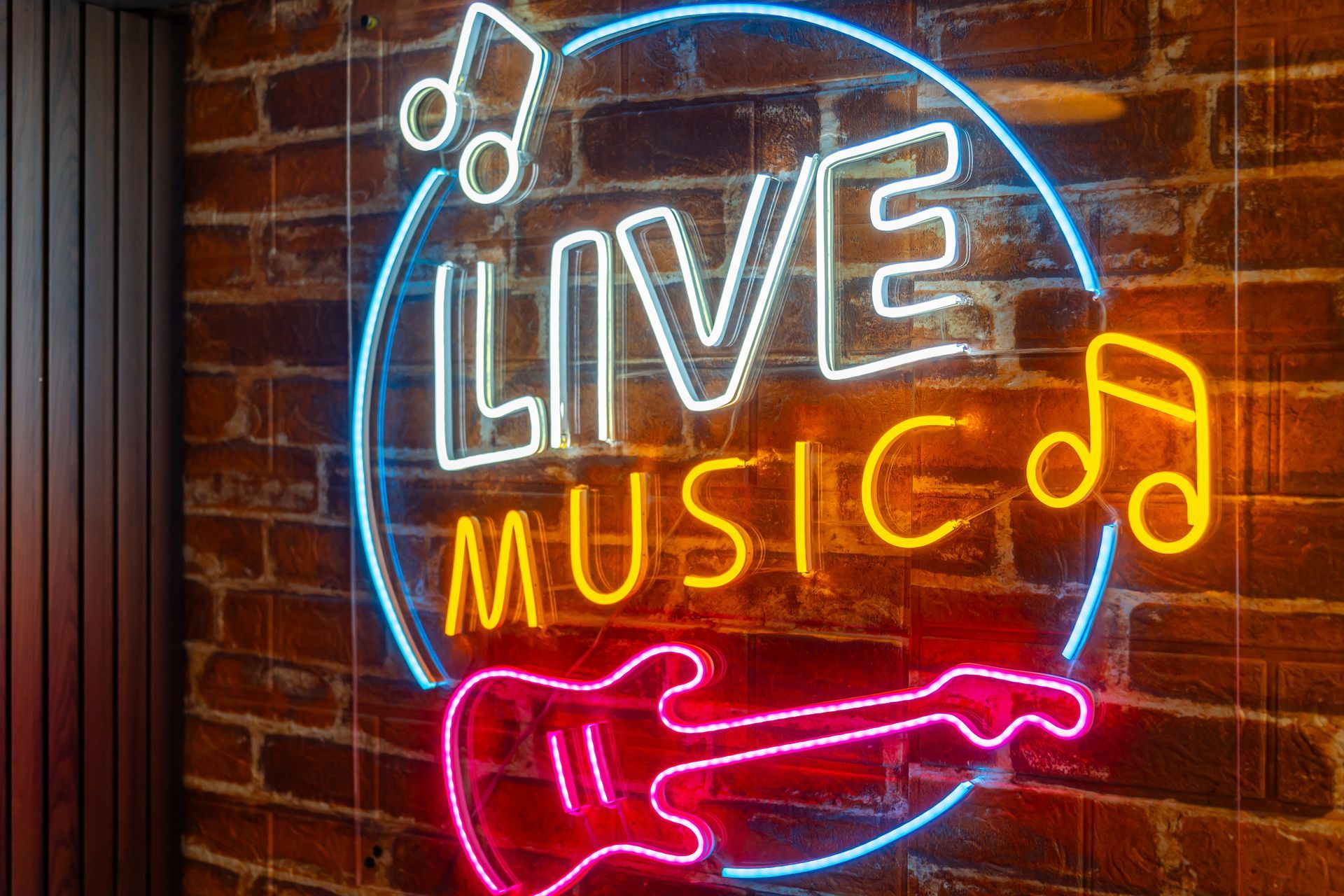 Neon white, yellow, pink and blue sign with Live Music, music notes and a guitar