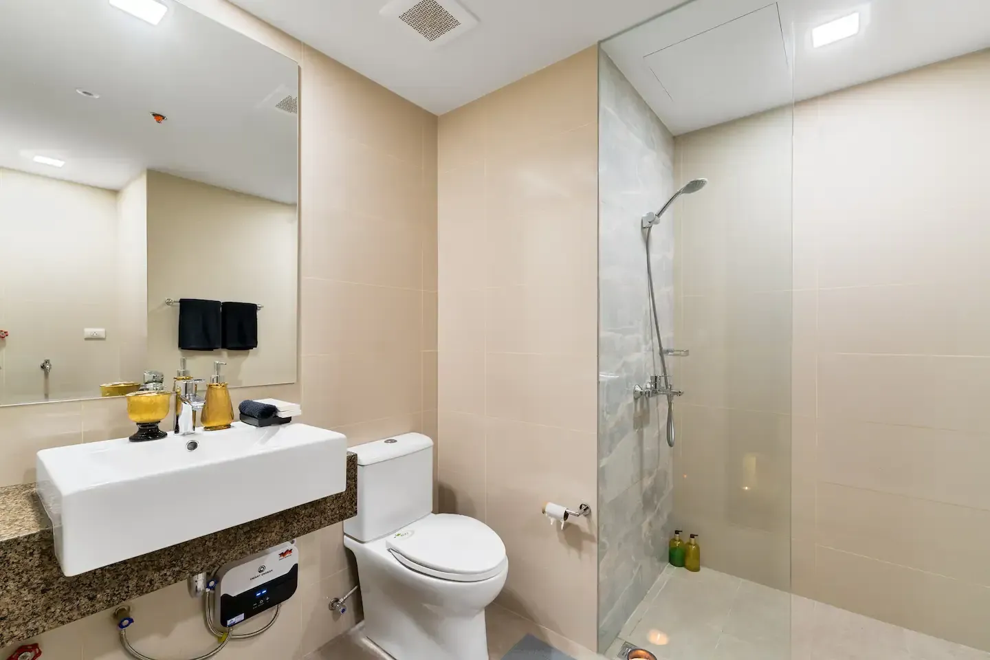 A bathroom with a toilet , sink and shower.   The Den at Bayshore Luxe by Prime, Manila